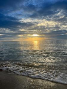 una puesta de sol sobre el océano en una playa en Cozy Khanom โคซี่ ขนอม en Ban Na Dan