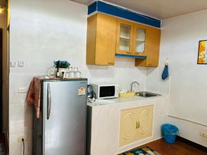 eine Küche mit einem Kühlschrank und einer Mikrowelle in der Unterkunft Condo Poppular T8 fl.7 in Thung Si Kan