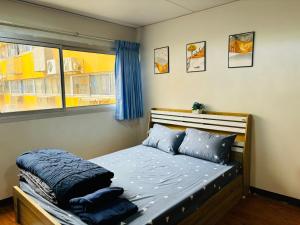 ein Schlafzimmer mit einem Bett mit blauen Kissen und einem Fenster in der Unterkunft Condo Poppular T8 fl.7 in Thung Si Kan