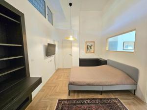 um pequeno quarto com uma cama e uma televisão em Grazioso bilocale ristrutturato vicino alla Stazione/metro em Milão