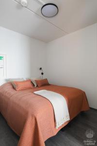 1 dormitorio con 1 cama con manta naranja en Holiday in Lapland - Ylläs Polar Charm B, en Ylläs