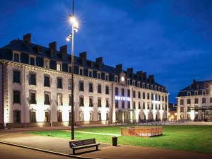 un edificio con un banco delante de él por la noche en Novotel Saint Brieuc Centre Gare en Saint-Brieuc