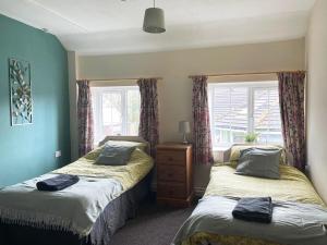 1 dormitorio con 2 camas y 2 ventanas en Alder Cottage, en Tiverton