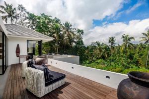 - un balcon avec des chaises en osier sur une terrasse en bois dans l'établissement The R Villa Cereme - nature, quite, luxurious, à Tegalalang