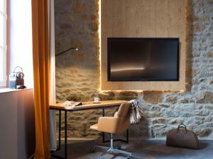 einen Schreibtisch mit Stuhl und einen TV an der Wand in der Unterkunft Novotel Saint Brieuc Centre Gare in Saint-Brieuc