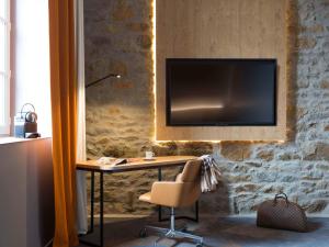 a desk with a chair and a television on a wall at Novotel Saint Brieuc Centre Gare in Saint-Brieuc