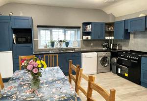 uma cozinha com armários azuis e uma mesa com flores em Alder Cottage em Tiverton