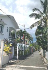 a street with a fence and a house and palm trees at Cheerful 1 bed vacation home with tours & facilities in La Gaulette