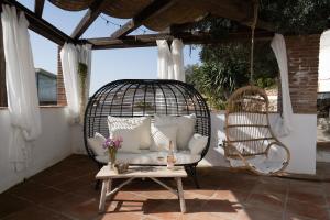 a porch with a swinging chair and a table at Hearts & Home in Mijas
