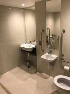 a bathroom with two sinks and a toilet at Holiday Inn London Kensington High St., an IHG Hotel in London