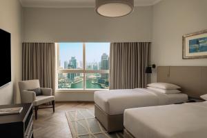 a hotel room with two beds and a large window at Dubai Marriott Harbour Hotel And Suites in Dubai