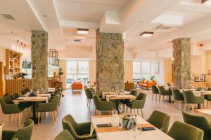 a restaurant with tables and green chairs at Country Club Żywiec Hotel SPA i Domki Całoroczne in Żywiec