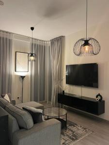ein Wohnzimmer mit einem Sofa und einem Flachbild-TV in der Unterkunft Dar Alsalam - Premium and Spacious 1BR With Balcony in Noor 2 in Dubai