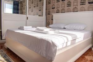 a bedroom with a white bed with white sheets and pillows at Sunset by Old Town in Constanţa