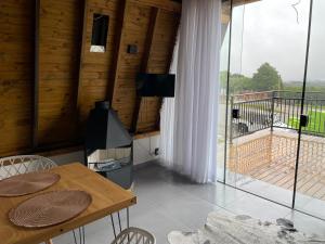 Habitación con mesa, sillas y balcón. en Pousada Portal dos campos, en Ponta Grossa