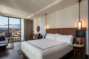 a bedroom with a large white bed with a view at Thompson Denver, by Hyatt in Denver