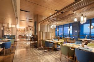 a restaurant with tables and chairs and windows at Hilton Garden Inn Zibo Zhangdian in Zibo