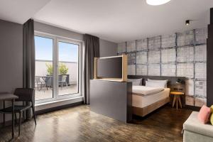 Un dormitorio con una cama y un balcón con una mesa. en Vienna House Easy by Wyndham Bremen City Apartments, en Bremen
