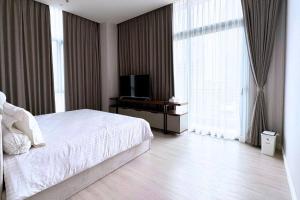 Schlafzimmer mit einem weißen Bett und einem TV in der Unterkunft Deluxe 2 BR Condo in Central Jakarta in Jakarta