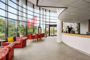 vestíbulo con muebles de color rojo, mesa y sillas en Amedia Amsterdam Airport, Trademark Collection by Wyndham - Free Parking, en Schiphol