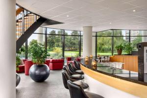 eine Lobby mit einer Bar, Stühlen und Fenstern in der Unterkunft Amedia Amsterdam Airport, Trademark Collection by Wyndham - Free Parking in Schiphol