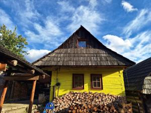 una casa amarilla con una ventana y un montón de troncos en Chata Vlkolínec, en Ružomberok