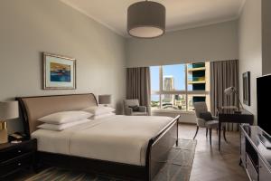 a bedroom with a bed and a desk and a window at Dubai Marriott Harbour Hotel And Suites in Dubai