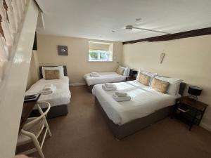 a hotel room with two beds and a desk at Rylands Farm Guest House in Wilmslow