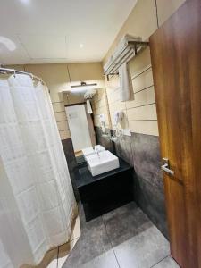 La salle de bains est pourvue d'un lavabo et d'un rideau de douche blanc. dans l'établissement Queens Tourist Home, à Badagara