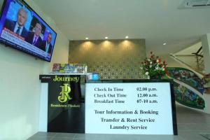 a room with a tv and a sign on the wall at Journey Residence Phuket in Bang Tao Beach