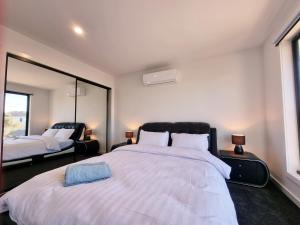 阳光海岸Brand new house - Mordern home and great location的卧室里有一张白色的大床和一面镜子 更多9张照片