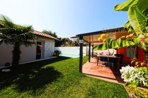 een achtertuin met een tafel en stoelen en een huis bij Jolie villa avec piscine chauffée in Anglet