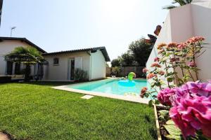 een zwembad in een tuin met roze bloemen bij Jolie villa avec piscine chauffée in Anglet