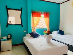 two beds in a room with blue walls and a window at Lanta Grand House in Ko Lanta