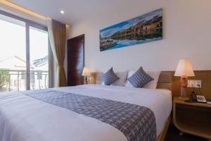 um quarto de hotel com uma cama e uma grande janela em Silk and Sea Hotel em Hoi An