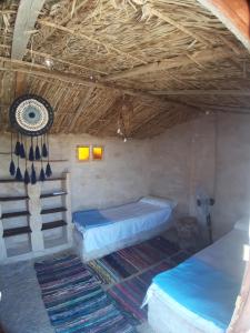 a room with two beds and a ceiling with a fan at M Biama Island in Siwa