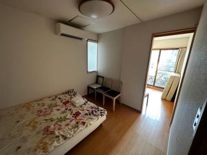 a bedroom with a bed and a table and a window at kaneshiro guest house in Tokyo