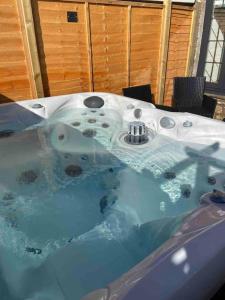 a bath tub filled with blue water in a room at Rural 5* Rookby Cottage, with large Hot Tub in Winton