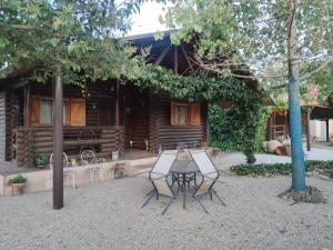 una mesa y sillas frente a una cabaña de madera en Casas Rurales Villa Pereza, en Casas de los Pinos