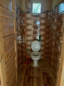 a small bathroom with a toilet with wooden walls at M Biama Island in Siwa