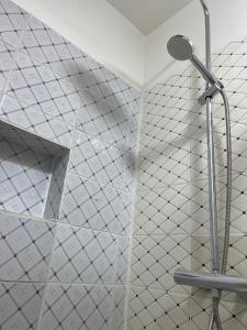 um chuveiro na casa de banho com azulejos brancos em Bastos'Appart YAOUNDE em Iaundé