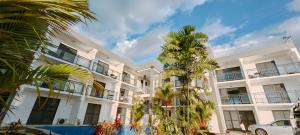 a white building with palm trees in front of it at Ocean Breeze Apartment in Nadi
