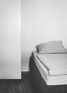 a bed in a room with a white wall at Die Praxis - Wohnen als Therapie in Arnstadt