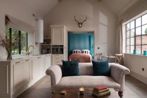 a living room with a couch and a kitchen at Blacksmith's Cottage in Nantwich