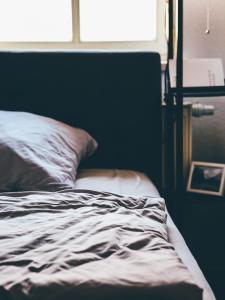 1 cama no hecha en un dormitorio con ventana en Die Praxis - Wohnen als Therapie, en Arnstadt