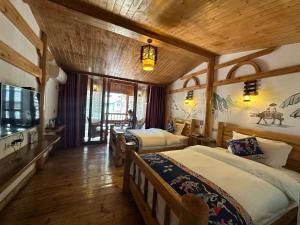 una camera con tre letti in una stanza con soffitti in legno di Mountain View Guesthouse a Zhangjiajie