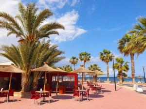 - une plage avec des tables, des chaises et des palmiers dans l'établissement Pure Beach Penthouse & Swimming pool, 3 bedrooms, à Los Alcázares