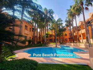 a swimming pool in front of a building with palm trees at Pure Beach Penthouse & Swimming pool, 3 bedrooms in Los Alcázares