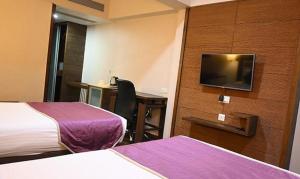 a hotel room with two beds and a desk and a tv at FabHotel Prime Ace Grand in Vadodara