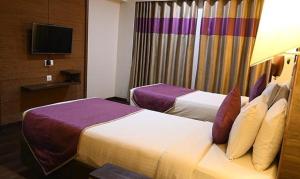 a hotel room with two beds and a television at FabHotel Prime Ace Grand in Vadodara